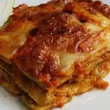 Una fetta di melanzane alla parmigiana, stratificata e dorata, con formaggio filante e sugo rosso.
