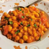 Piatto di ceci e pomodoro, guarnito con prezzemolo. Un sapore che ricorda la peretta formaggio, un classico.