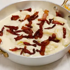 Gnocchi soffici in una cremosa fonduta, guarniti con croccante pancetta. Un piatto che invita alla gola.