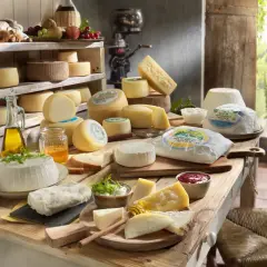 Un ricco assortimento per una presentazione tagliere formaggi: diverse varietà, miele, olio e pane su un tavolo rustico.