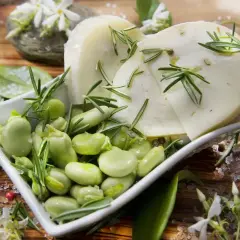 Baccelli freschi e fette di pecorino guarnite con rosmarino su un tagliere di legno.