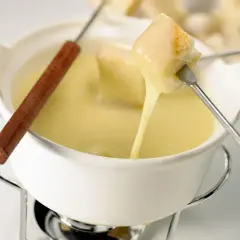 Un pezzo di pane viene intinto in una cremosa fonduta di stracchino, che cola filante.