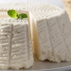 Formaggi freschi, uno a spicchi, con decorazioni a righe e un rametto di basilico. Perfetti per una deliziosa fonduta di Asiago.