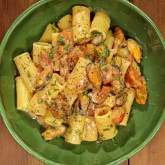 Rigatoni con cozze e pomodorini, conditi con una cremosa salsa al pecorino e prezzemolo fresco.