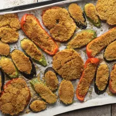 Verdure gratinate al forno con formaggio, un tripudio di sapori e colori su una teglia. Melanzane, zucchine e peperoni ripieni di pangrattato croccante.
