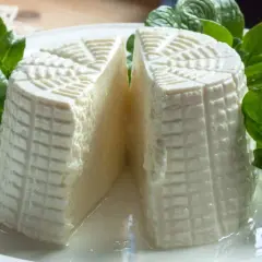 Formaggio fresco a forma cilindrica, tagliato a metà, con decorazioni a griglia. Se cerchi come sostituire la tuma, questo fresco latticino è un'ottima alternativa.