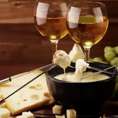 Fonduta di formaggio con pane e uva, accompagnata da vino bianco. Un'ottima fonduta di formaggio con cosa si accompagna? Con questi ingredienti, è perfetta!