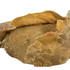 Blocco di caglio animale essiccato, di colore giallo-marrone, con una consistenza irregolare e sfogliata.