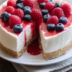 Delizioso cheesecake con mascarpone, guarnito con lamponi freschi, mirtilli e una colata di salsa rossa.