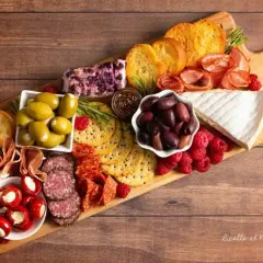 Tagliere ricco di antipasti sfiziosi: salumi, formaggi, olive, lamponi e crostini. Un tripudio di sapori e colori.