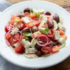 Insalata fresca con pomodorini, olive, cipolla rossa e cubetti di feta, condita con erbe aromatiche.
