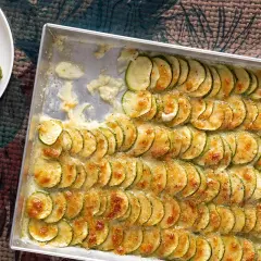 Zucchine al forno con mozzarella, disposte a raggiera in una teglia, dorate e filanti. Un piatto semplice e gustoso.