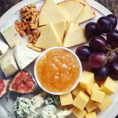 Vassoio con formaggi misti, uva, fichi, noci e una ciotola di composta di pere per formaggi.