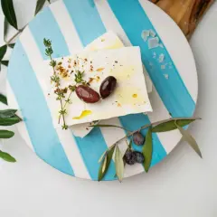 Blocchi di feta conditi con erbe e olive, pronti per essere gustati. Un'ispirazione su come fare la feta in casa.