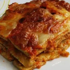 Una fetta di melanzane alla parmigiana, stratificata e dorata, con formaggio filante e sugo rosso.