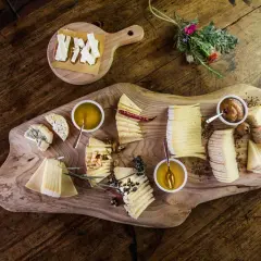 Assaggio di formaggi su tagliere rustico, ideale per un corso assaggiatore formaggi. Diverse varietà con miele e confetture.