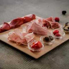 Un invitante tagliere di antipasti con salumi, olive, pomodorini e frutti di bosco, pronto per essere gustato.