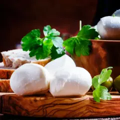 Mozzarelle fresche su tagliere di legno, con pane, olive e prezzemolo. Un'idea per un antipasto leggero, considerando le mozzarelle calorie.