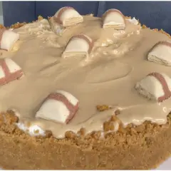 Cheesecake con copertura cremosa e pezzi di Kinder Bueno, un dolce irresistibile per gli amanti del cioccolato.