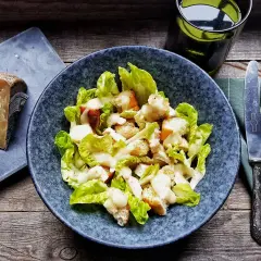 Insalata Caesar con crostini e una generosa spolverata di crema di pecorino. Accanto, un pezzo di formaggio stagionato.