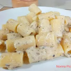 Un piatto di pasta cacio e pepe, con rigatoni cremosi e pepe nero macinato.