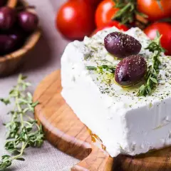 Blocco di feta condito con olive e erbe aromatiche, perfetto per scoprire quante calorie ha la feta in una gustosa insalata greca.
