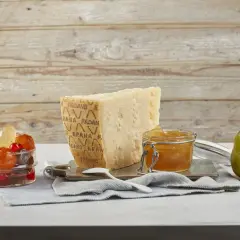 Un pezzo di Grana Padano stagionato, un vasetto di miele dorato e frutta candita, pronti per un abbinamento delizioso.