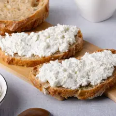 Fette di pane rustico con ricotta fresca, un'ottima scelta per scoprire i benefici della ricotta.