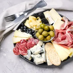 Bei taglieri con salumi, formaggi misti, olive verdi, frutti di bosco e cracker.
