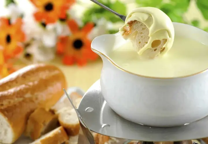 Un pezzo di pane intinto in una fonduta cremosa, un modo delizioso per sciogliere il formaggio.