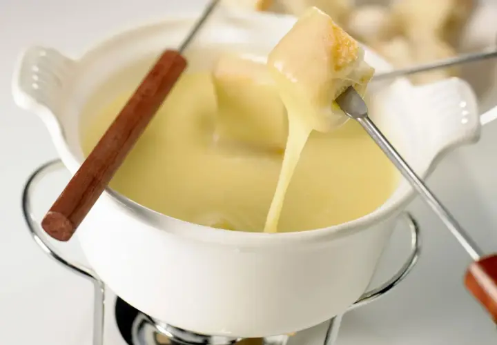 Un pezzo di pane viene intinto in una cremosa fonduta di stracchino, che cola filante.