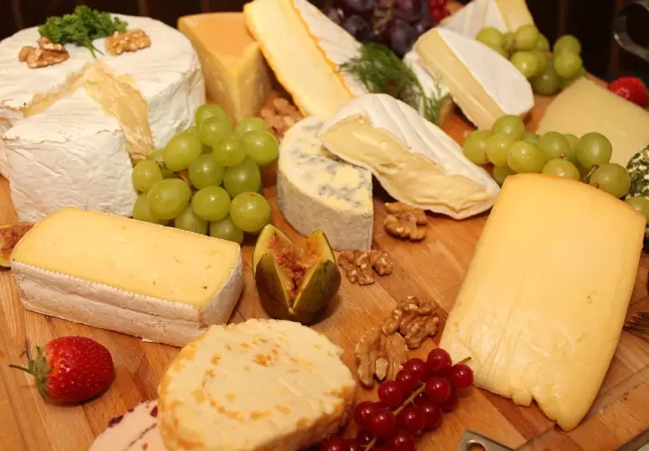 Un ricco assortimento di formaggi tipi, con uva, fichi, noci e fragole, perfetto per un aperitivo gourmet.