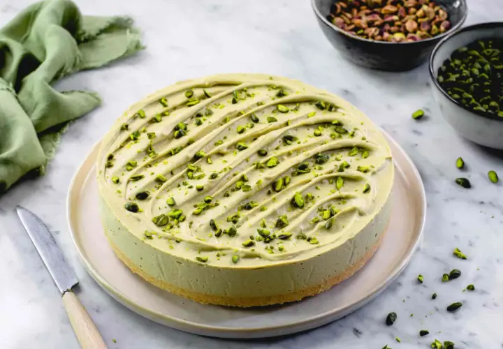 Delizioso cheesecake al pistacchio, guarnito con granella verde brillante. Un tripudio di gusto e colore.