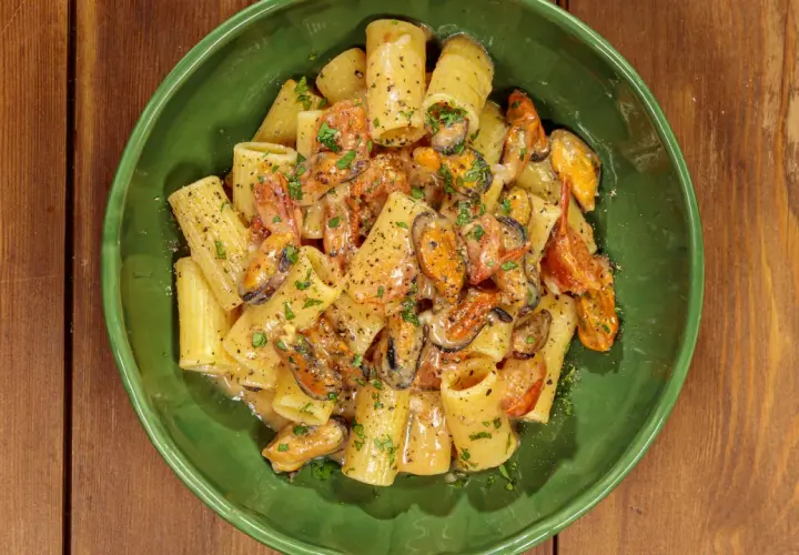 Rigatoni con cozze e pomodorini, conditi con una cremosa salsa al pecorino e prezzemolo fresco.
