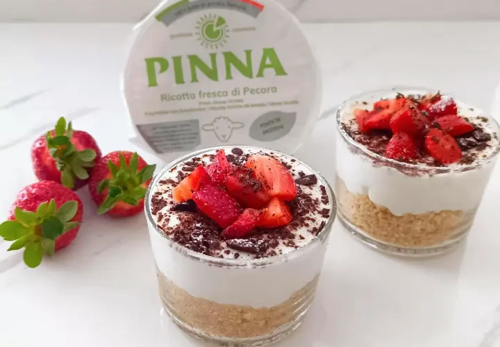 Delizioso dolce al bicchiere con ricotta fresca, fragole e scaglie di cioccolato. Perfetto per un dessert leggero e gustoso.