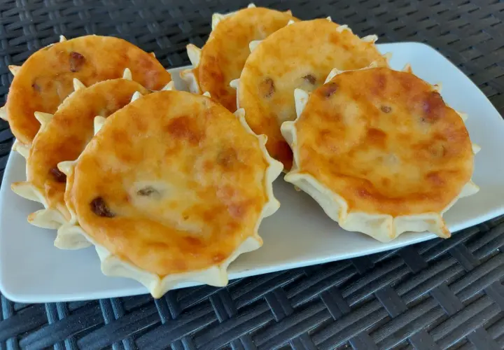 Sei formaggelle di formaggio dorate e invitanti, disposte su un piatto bianco.