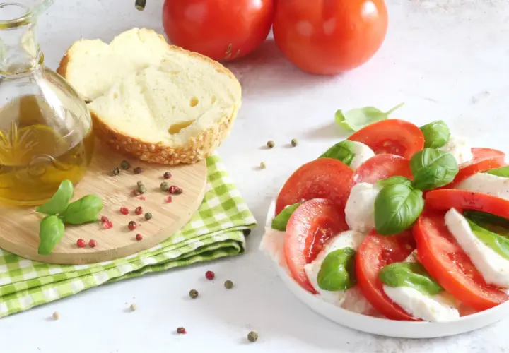 Un'incredibile insalata caprese, con pomodori freschi, mozzarella e basilico, pronta per essere condita con olio d'oliva.