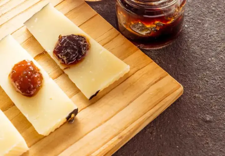 Fette di formaggio con miele e marmellata su tagliere. Perfetto per capire quanto può stare il formaggio fuori dal frigo.