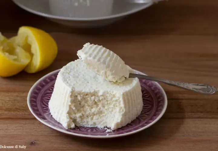 Ricotta fresca su piatto viola, con limone e cucchiaino. Perfetta per ogni ricetta.