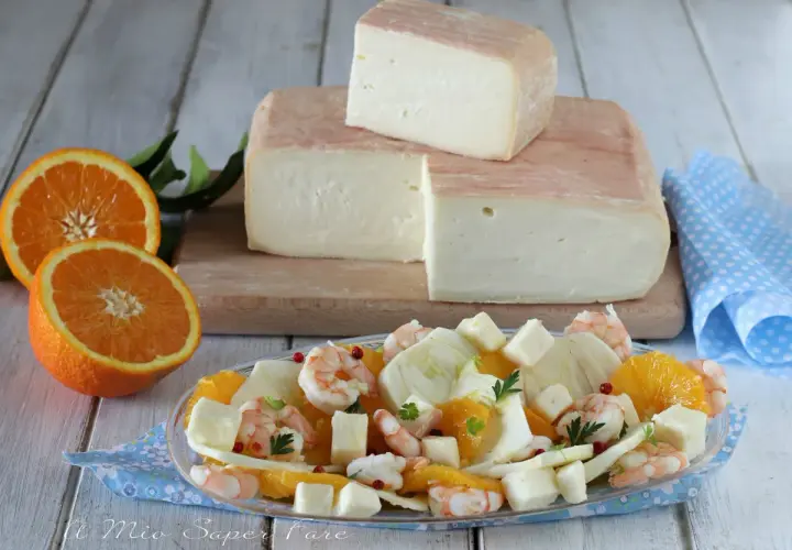 Un blocco di formaggio taleggio stagionato, pronto per essere gustato con un'insalata fresca di arance, finocchi e gamberetti.