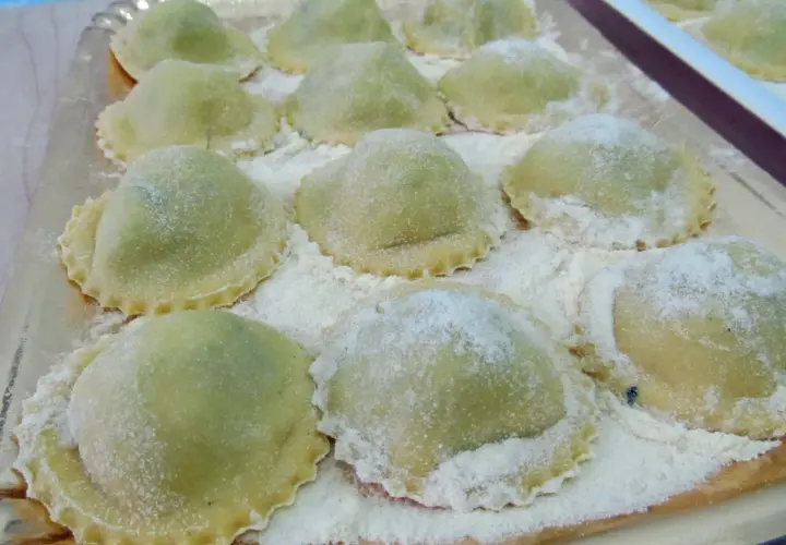 Ravioli verdi su vassoio, perfetti con cosa sostituire la ricotta nella dieta.