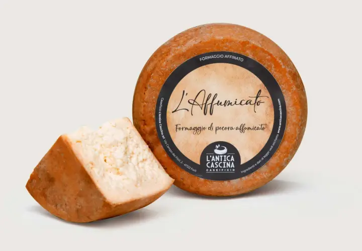 Formaggio di pecora affumicato, con una fetta tagliata. L'etichetta riporta "L'Affumicato" e "Formaggio di pecora affumicato".