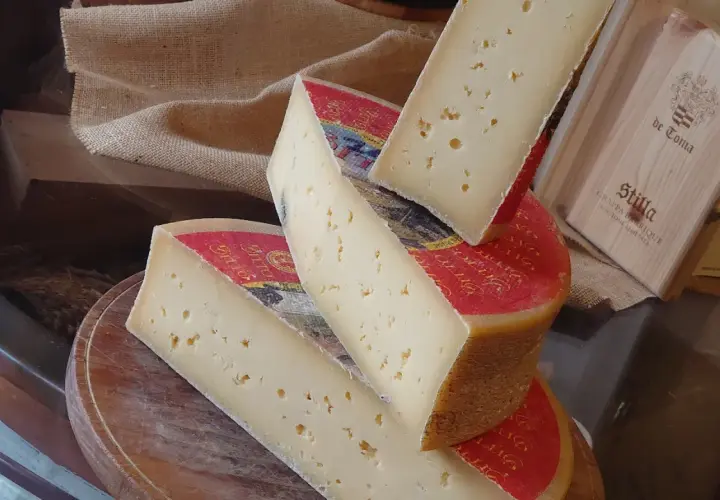 Fette di formaggio stagionato, con buchi, su un tagliere. Attenzione, la scamorza fa ingrassare!