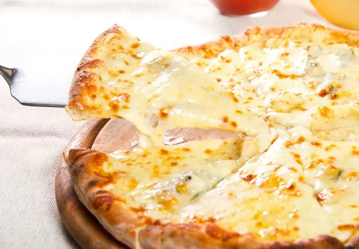 Una fetta di pizza ai 4 formaggi filante viene sollevata da una pala, mostrando la crosta dorata e il formaggio fuso.