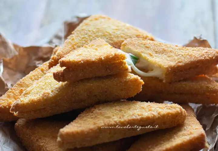 Triangoli dorati di formaggio in carrozza, con il formaggio filante che fuoriesce da uno.