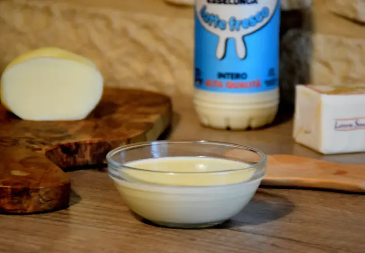 Una ciotola di cremosa fonduta di scamorza affumicata, con latte fresco e burro, pronta per essere gustata.
