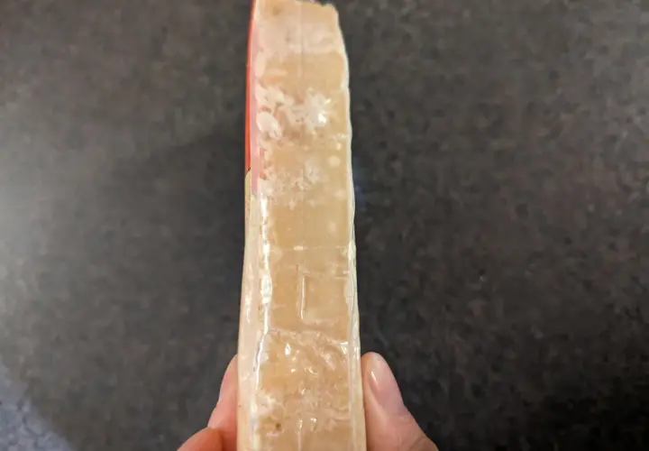 Un pezzo di formaggio stagionato, forse formaggio scaduto si può mangiare se non presenta muffe strane.