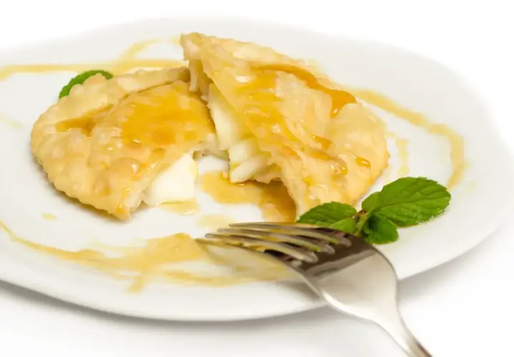 Seadas al miele, un dolce fritto ripieno di formaggio, irrorato di miele dorato e guarnito con menta fresca.