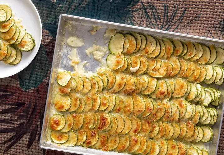Zucchine al forno con mozzarella, disposte a raggiera in una teglia, dorate e filanti. Un piatto semplice e gustoso.