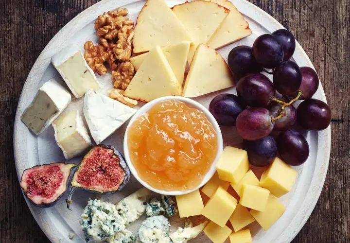 Vassoio con formaggi misti, uva, fichi, noci e una ciotola di composta di pere per formaggi.